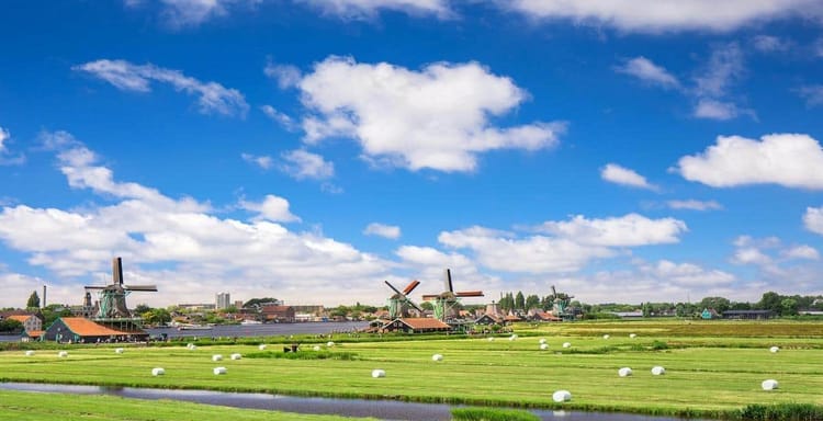 Colorful Dutch windmills in the scenic Dutch countryside with lush green fields and blue sky.