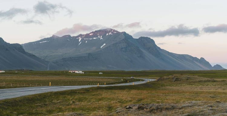 Scenic Icelandic mountain landscape with winding road and expansive green fields for travel planning.