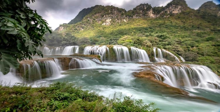Stunning waterfall cascading over lush green mountainside with vibrant natural scenery.