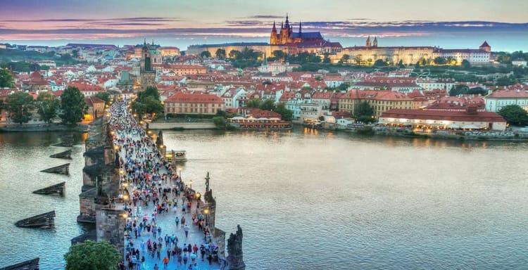 Historic Charles Bridge in Prague at dusk, showcasing Czech architecture and scenic views.