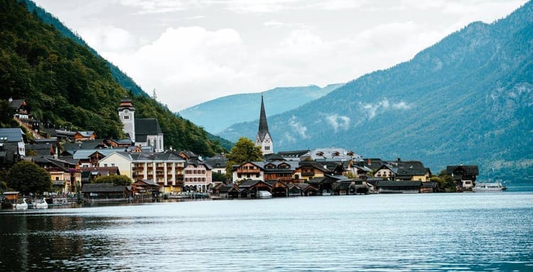 Serene lakeside village with mountains, perfect for travel planning and direction services.