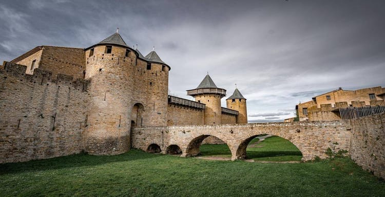 Medieval stone castle with round towers and stone bridge, historic fortress in rugged landscape, QuestForDirections.