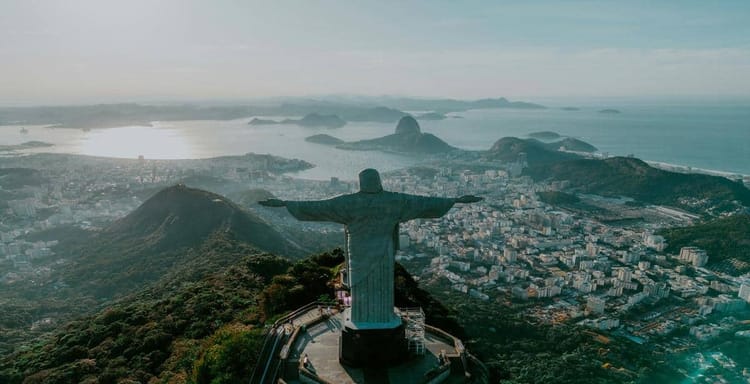 Panoramic view of Rio de Janeiro featuring Christ the Redeemer statue overlooking the city and Atlantic Ocean.