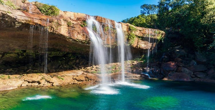 Waterfall at a scenic nature destination, lush greenery, and relaxing turquoise pool, perfect for outdoor adventures and sightseeing.