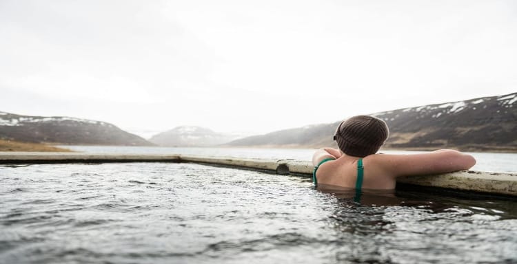Child relaxing in outdoor hot spring with mountain view, exploring nature and outdoor adventures.