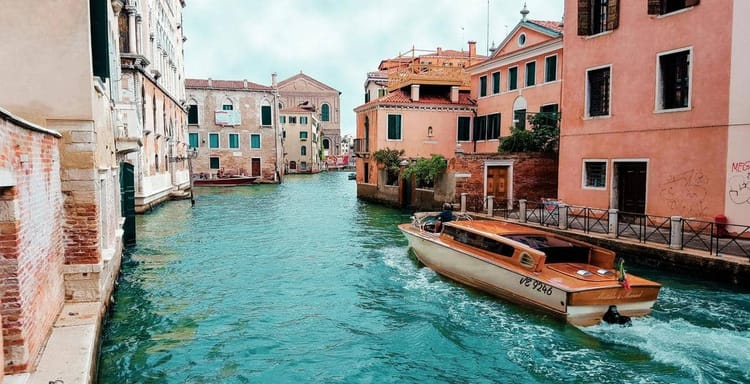 Venezia canal with boat, colorful buildings in Italy, popular travel destination, waterfront scenery.