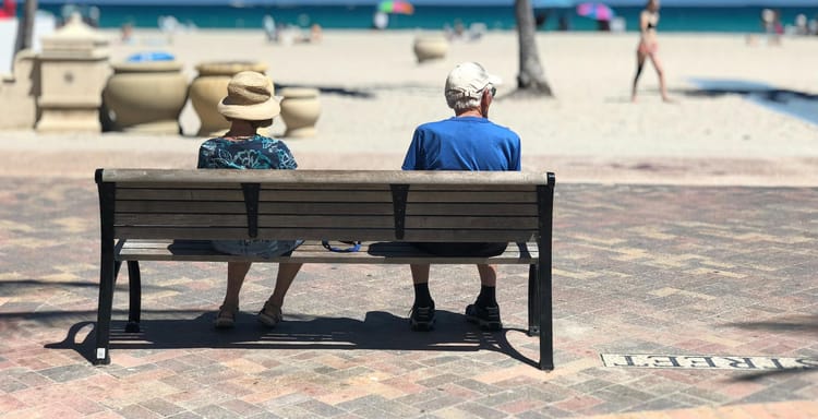Senior couple sitting on a bench enjoying a sunny day at Hollywood Beach, Florida.