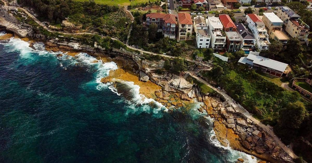 Cliffside residential neighborhood overlooking ocean with rocky shoreline and modern homes.