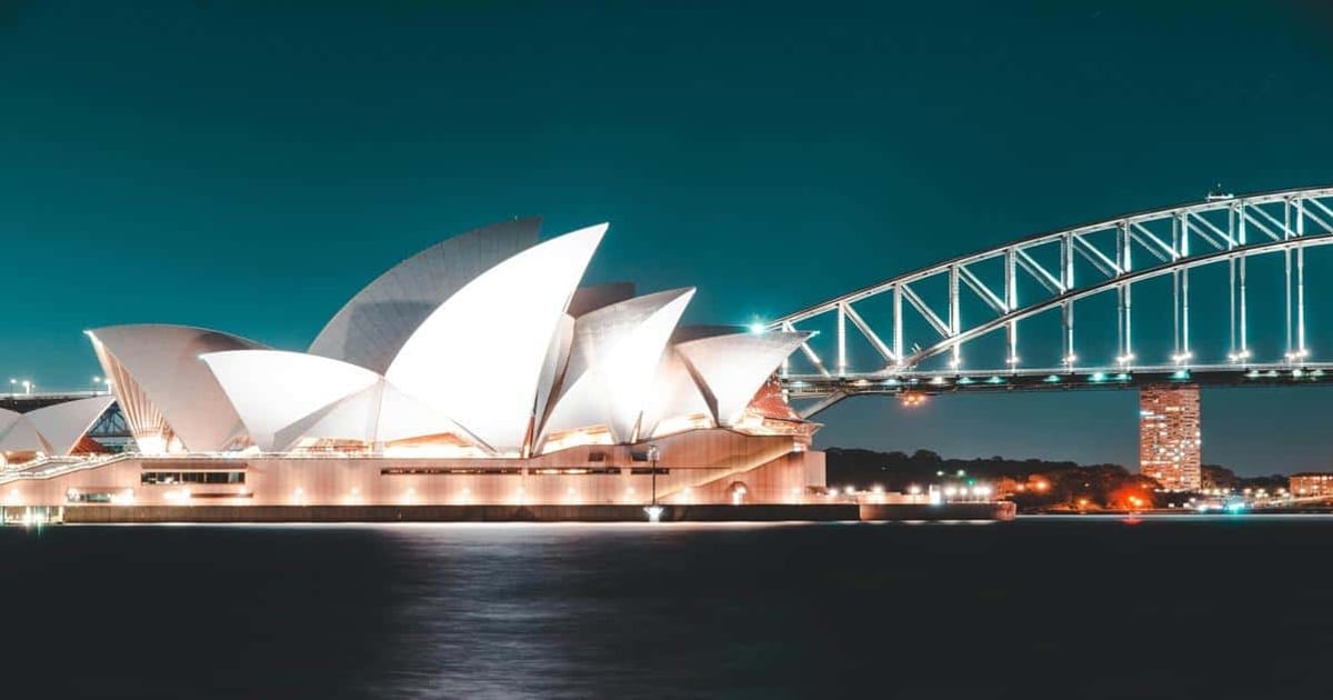 Sydney Opera House illuminated at night with Harbour Bridge, iconic tourist destination in Australia.