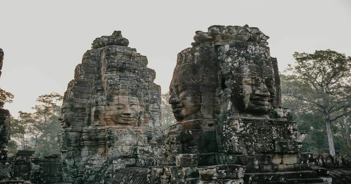 Ancient Angkor Wat stone faces at sunrise in Cambodia, showcasing historical and cultural tourism.