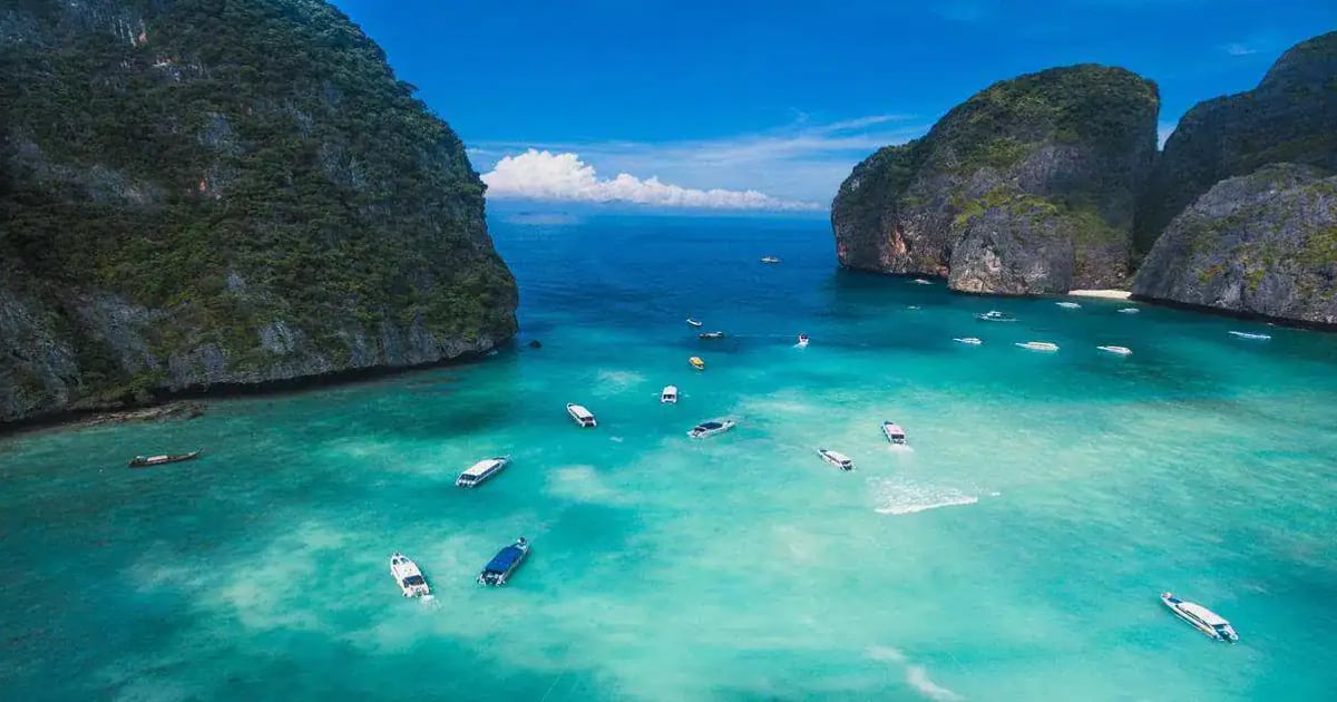 Turquoise bay with boats near limestone cliffs, scenic travel destination, Thailand island paradise.