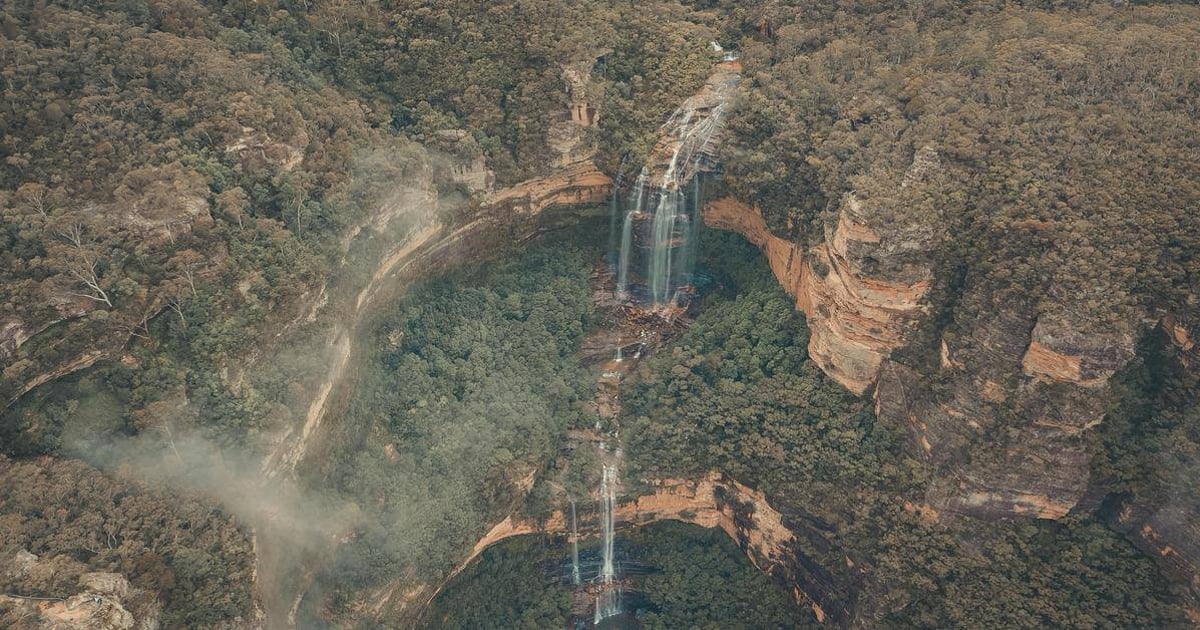 Stunning aerial view of a waterfall in a lush, green forest landscape at QuestForDirections.