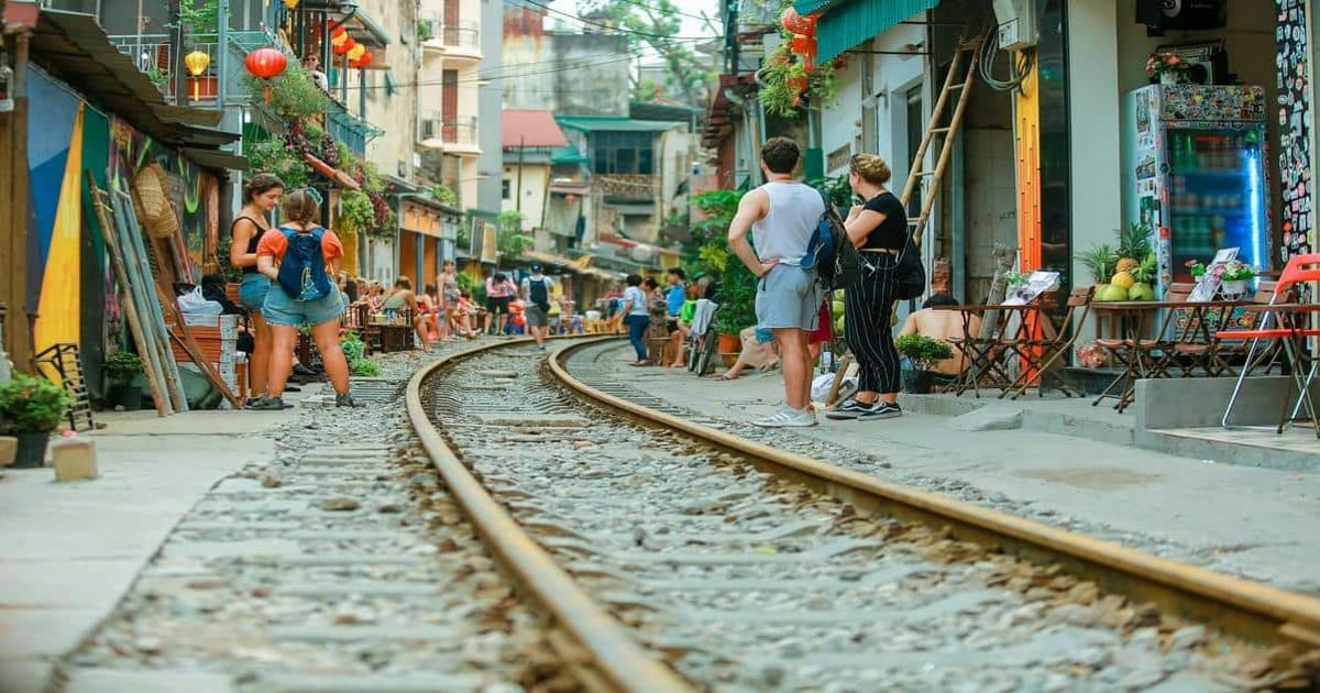 Colorful urban street scene with railway tracks, tourists, and local shops in a vibrant neighborhood.