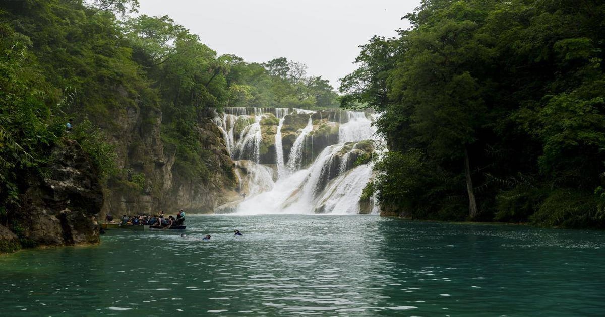 Vibrant waterfall surrounded by lush green trees at QuestForDirections adventure travel site.