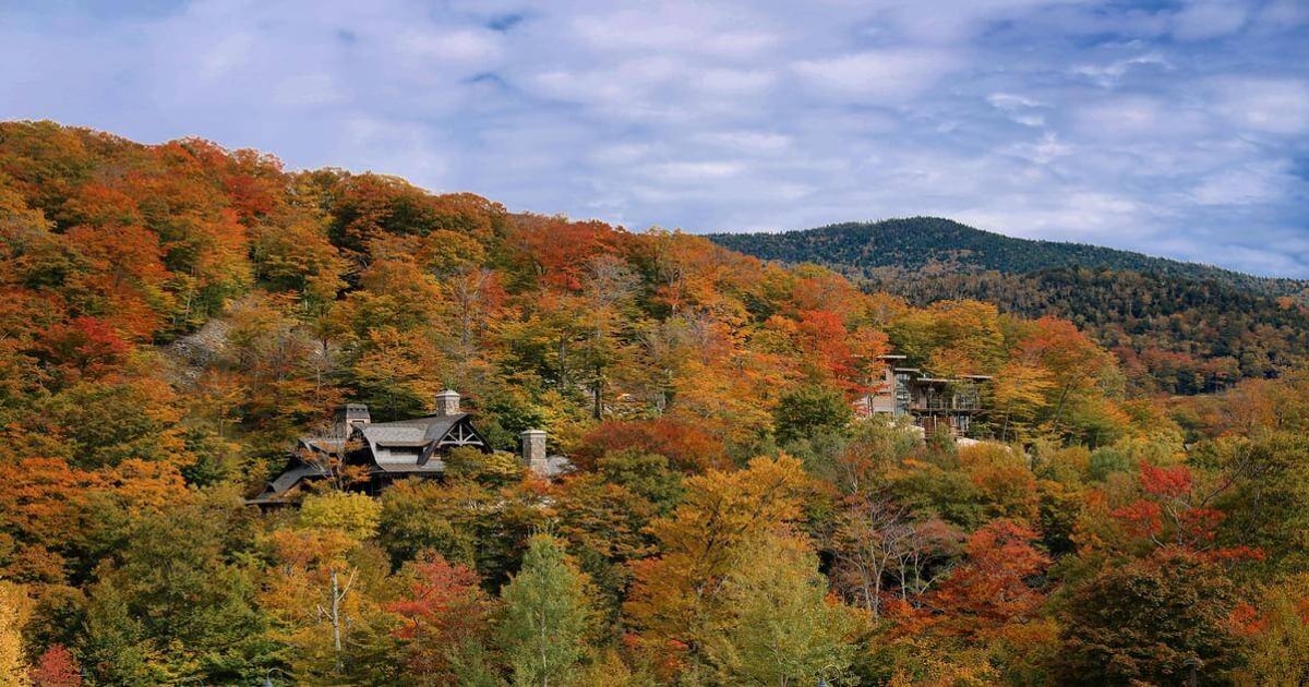 Colorful fall foliage with scenic mountains and rustic homes in autumn.