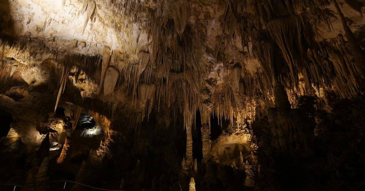 Ancient cave formations with stalactites and stalagmites, illuminated inside a natural underground cavern.