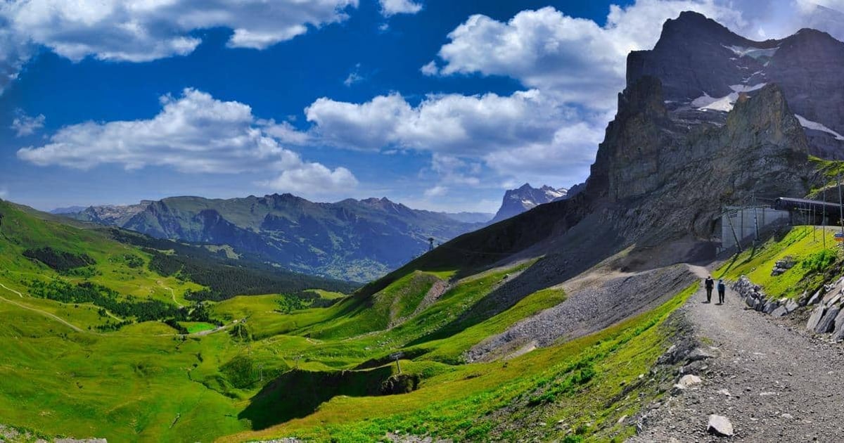 Vibrant mountain landscape with hiking trail, lush green valleys, and dramatic peaks. Perfect for adventure and outdoor travel guides.