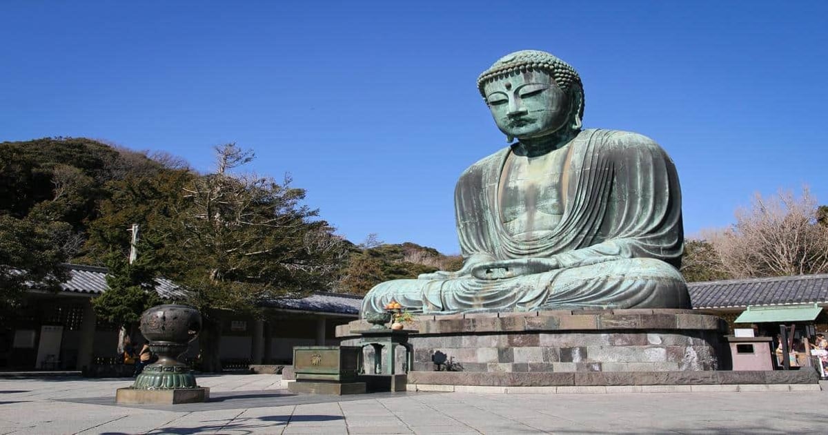 Huge bronze Buddha statue at historical temple grounds in Japan, peaceful spiritual site for visitors.