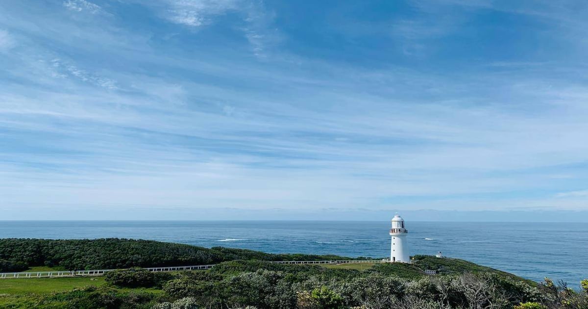 Lighthouse overlooking the ocean on scenic coastal landscape for travel navigation.
