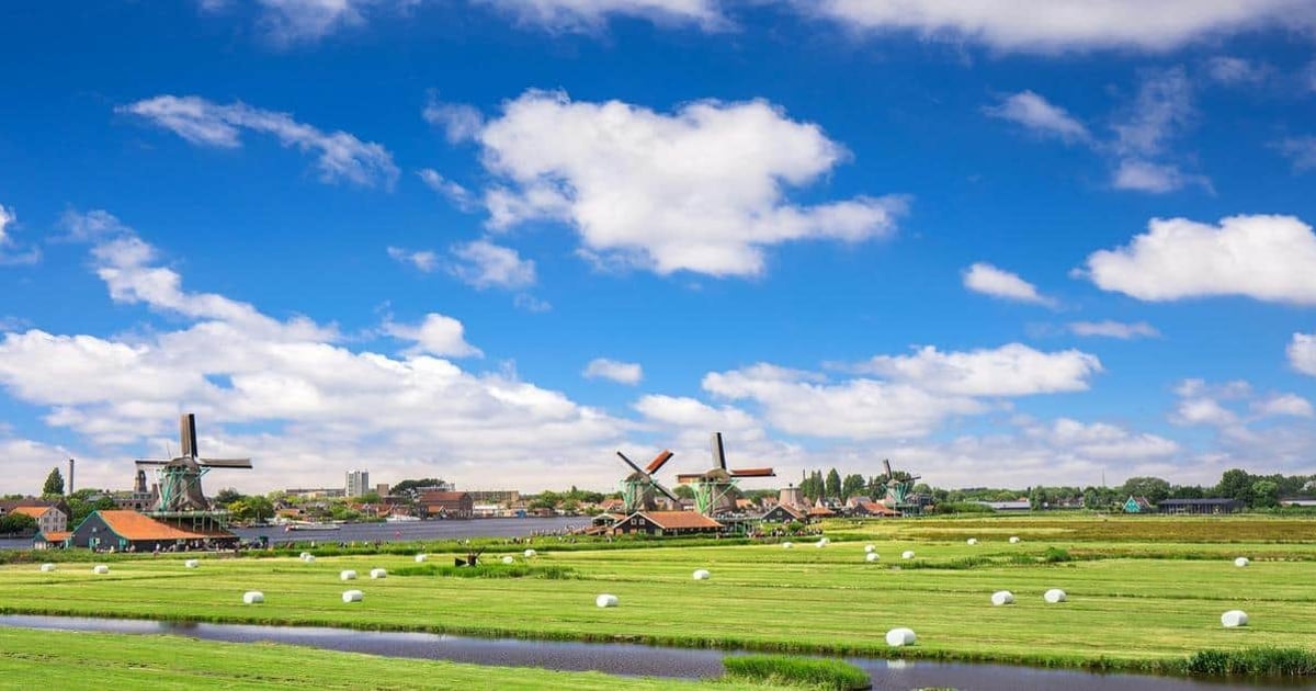 Colorful Dutch windmills in the scenic Dutch countryside with lush green fields and blue sky.