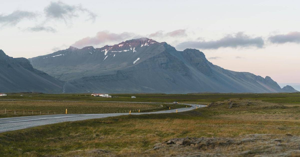Scenic Icelandic mountain landscape with winding road and expansive green fields for travel planning.