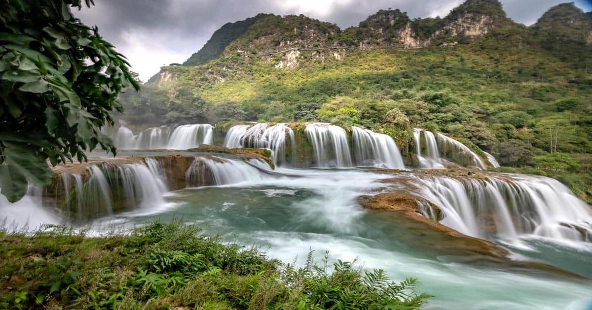 Stunning waterfall cascading over lush green mountainside with vibrant natural scenery.