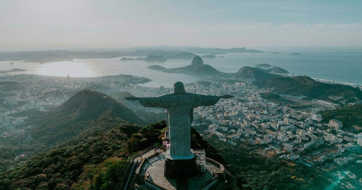 Panoramic view of Rio de Janeiro featuring Christ the Redeemer statue overlooking the city and Atlantic Ocean.