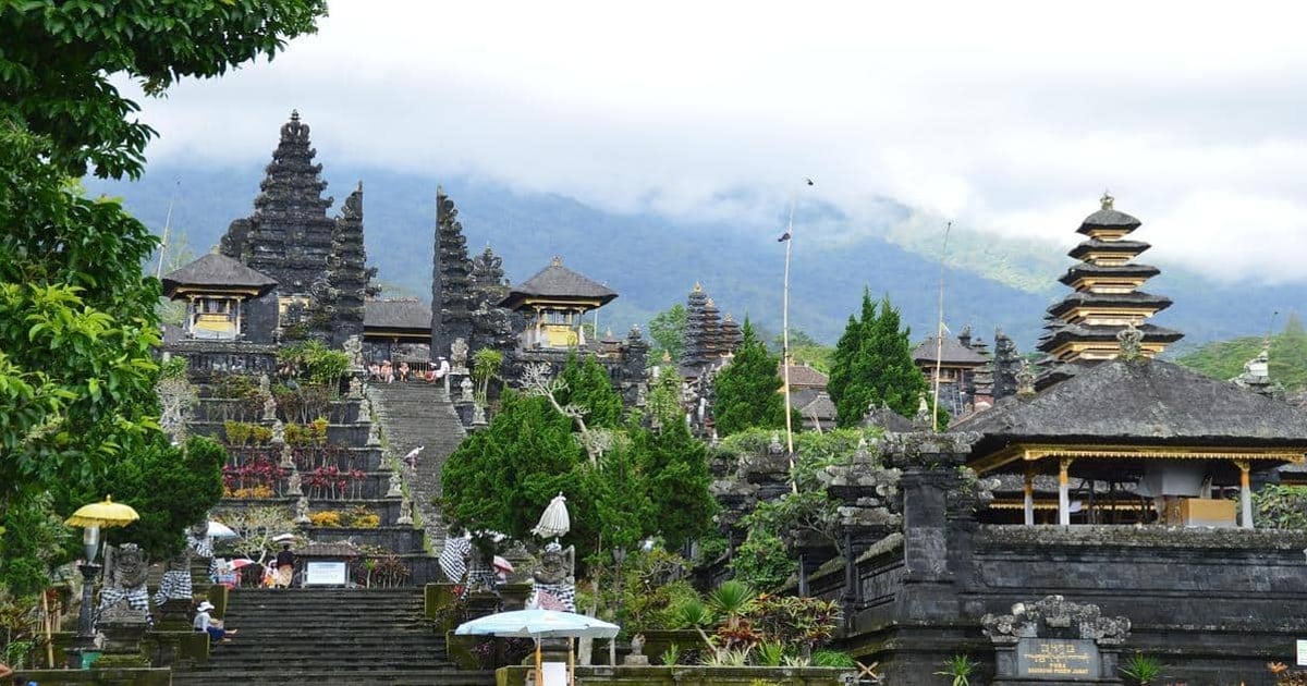 Ancient Balinese Hindu temple with stone carvings and lush greenery in a mountain setting.