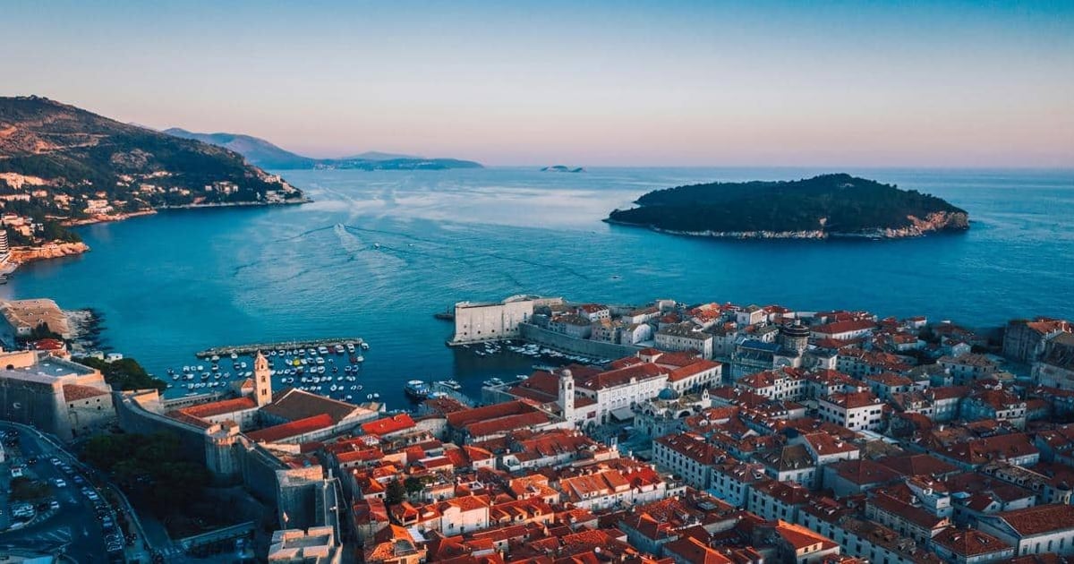 Panoramic view of Dubrovnik Old Town with red rooftops, fortress walls, and Adriatic Sea coastline.