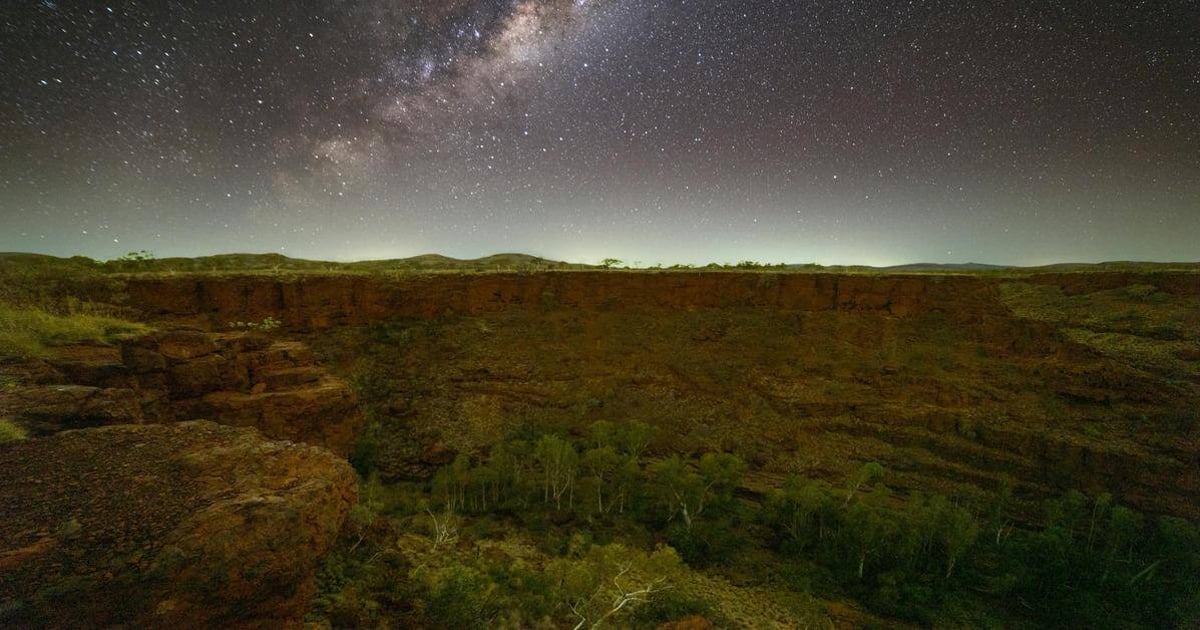 Stargazing over a desert canyon at night with the Milky Way in the sky.