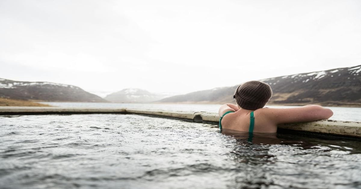 Child relaxing in outdoor hot spring with mountain view, exploring nature and outdoor adventures.