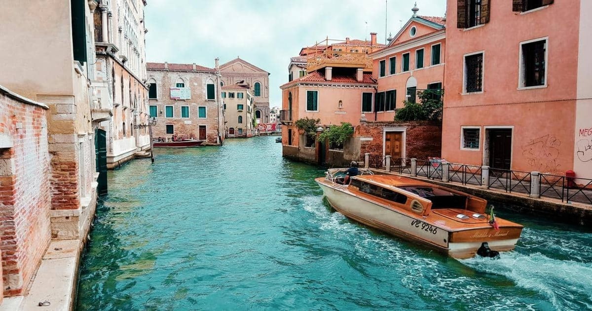 Venezia canal with boat, colorful buildings in Italy, popular travel destination, waterfront scenery.